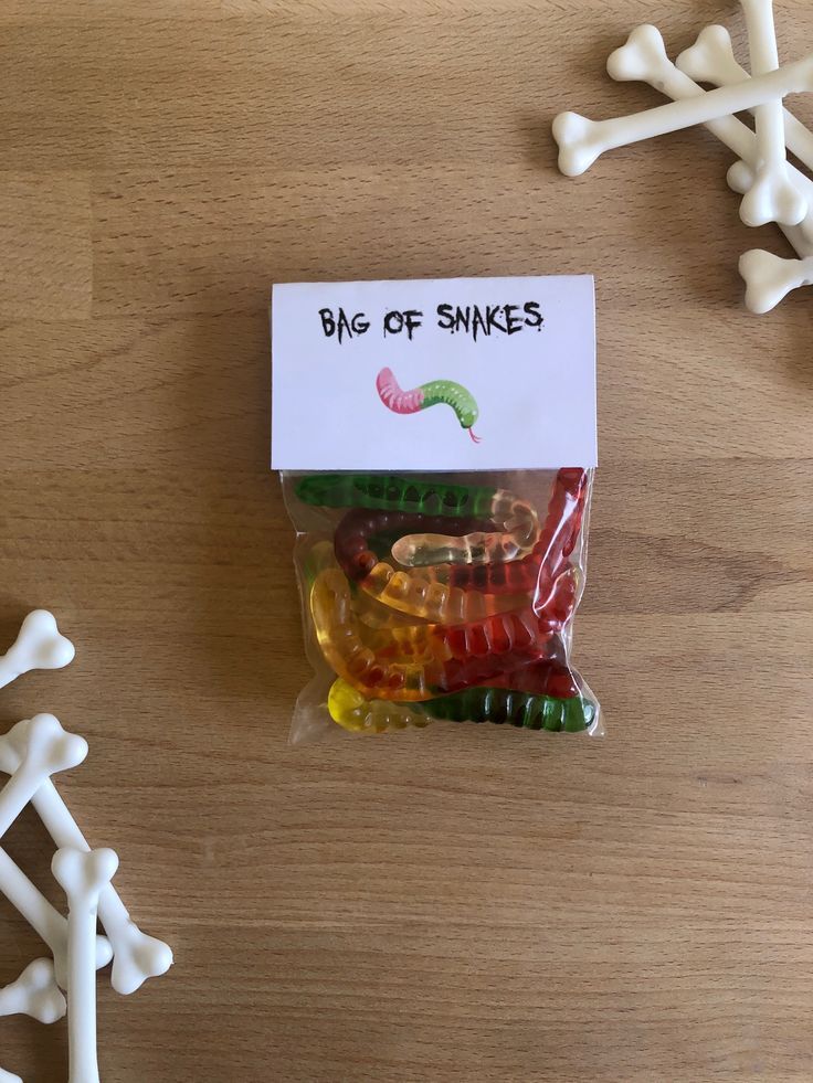 a bag of gummy bears sitting on top of a wooden table next to bones