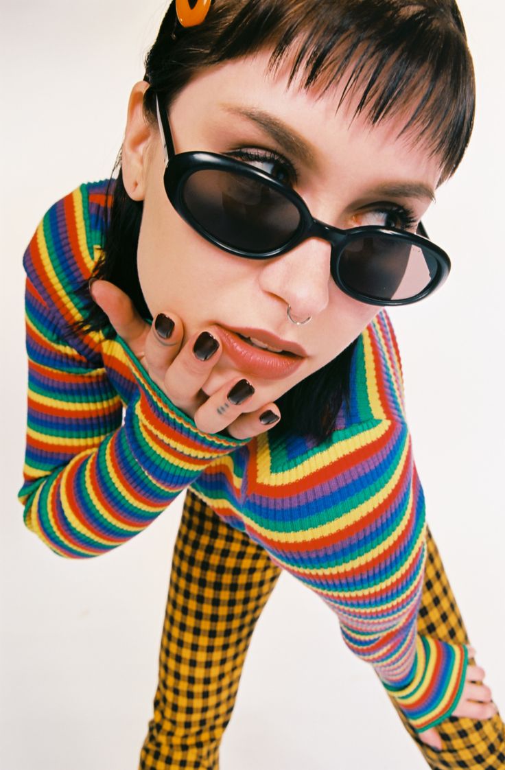 a woman with black nails and sunglasses on her face is posing for the camera while wearing colorful clothing