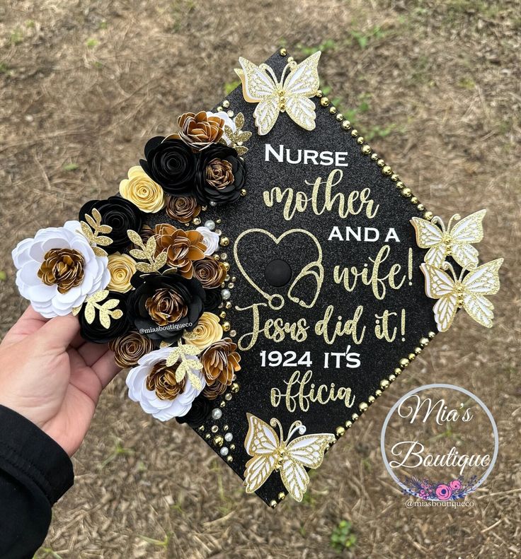 a hand holding a decorated graduation cap with flowers on it that says nurse and daughter