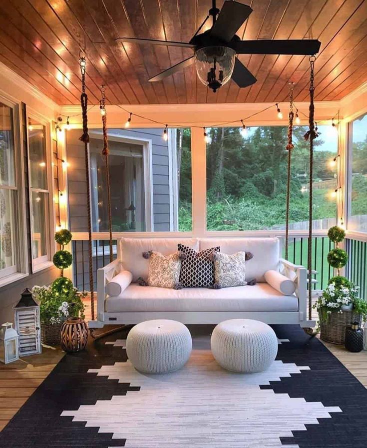 a white couch sitting on top of a black and white rug under a ceiling fan