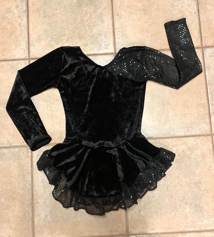 "This custom made, long-sleeved dress is made of a black VELVET with the sleeves and ruffled hem made of a black confetti dot, sequined material. Has a high neckline with lower back. The skirt is gathered at the waist and attached underneath is the matching brief. Measurements: SIZE BUST WAIST HIPS GIRTH 4-6 20-21\" 19-20\" 22-23\" 37-38\" 6x-7 22-23\" 20-21\" 23-25\" 41-42\" 8-10 24-25\" 21-22\" 25-27\" 44-45\" 12-14 26\" 22-23\" 27-29\" 46-48\"" Black Fitted Dance Dress, Black Fitted Dress For Dance, Black Stretch Dress For Dance, Black Sequin Stretch Dress, Fitted Long Sleeve Sequin Dress For Fall, Fitted Long Sleeve Dress With Sequins For Fall, Fitted Sequin Dance Dress, Fitted Sequin Dress For Dance, Black Costume Dress For Winter