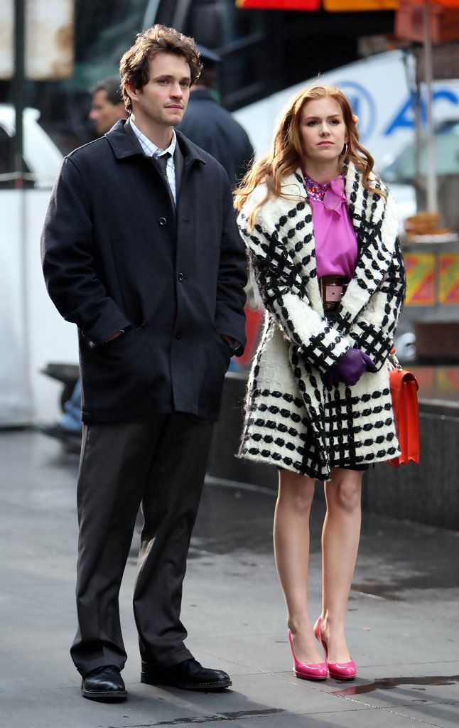 a man standing next to a woman on a city street while holding an orange purse