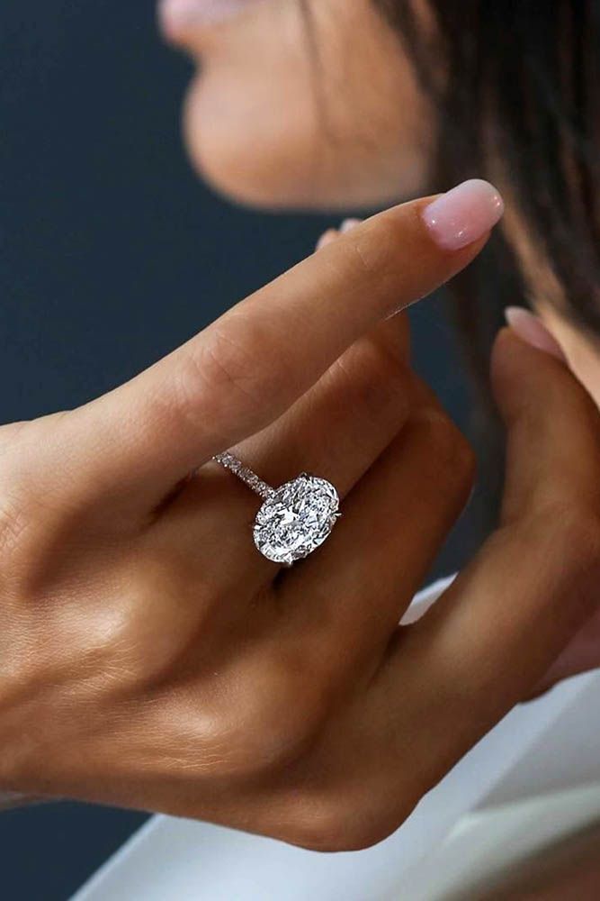 a woman's hand with a diamond ring on her finger, looking at the camera