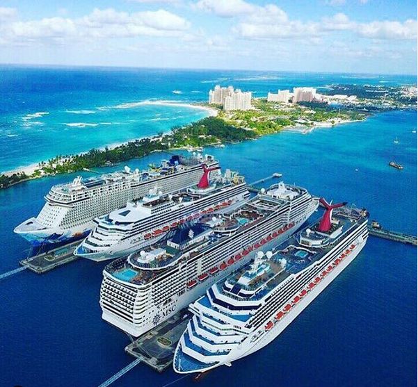 two cruise ships are docked in the water next to each other near an island and some buildings