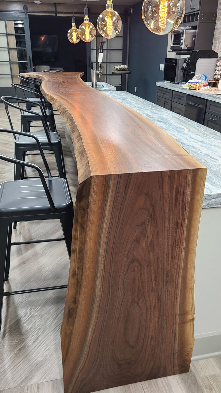 a wooden counter top sitting in the middle of a kitchen next to bar stools