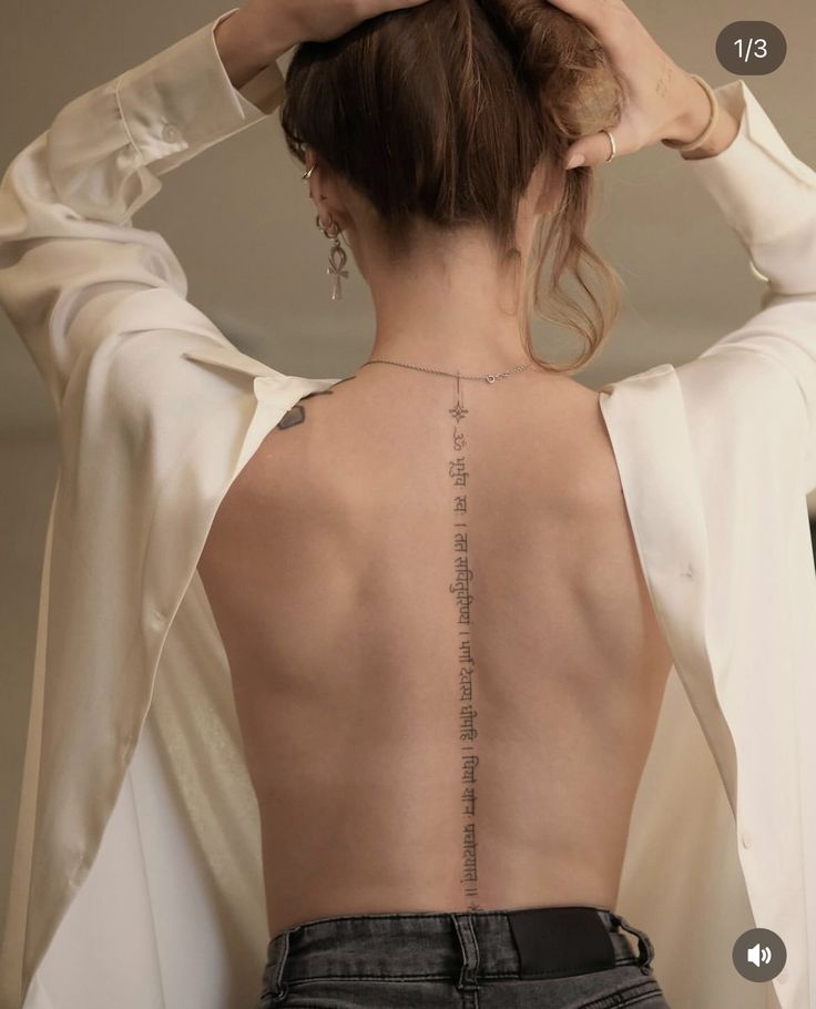 the back of a woman's body with chinese writing on her upper back tattoo