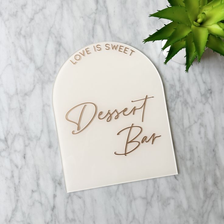 a sign that says love is sweet dessert bar on it next to a plant with leaves