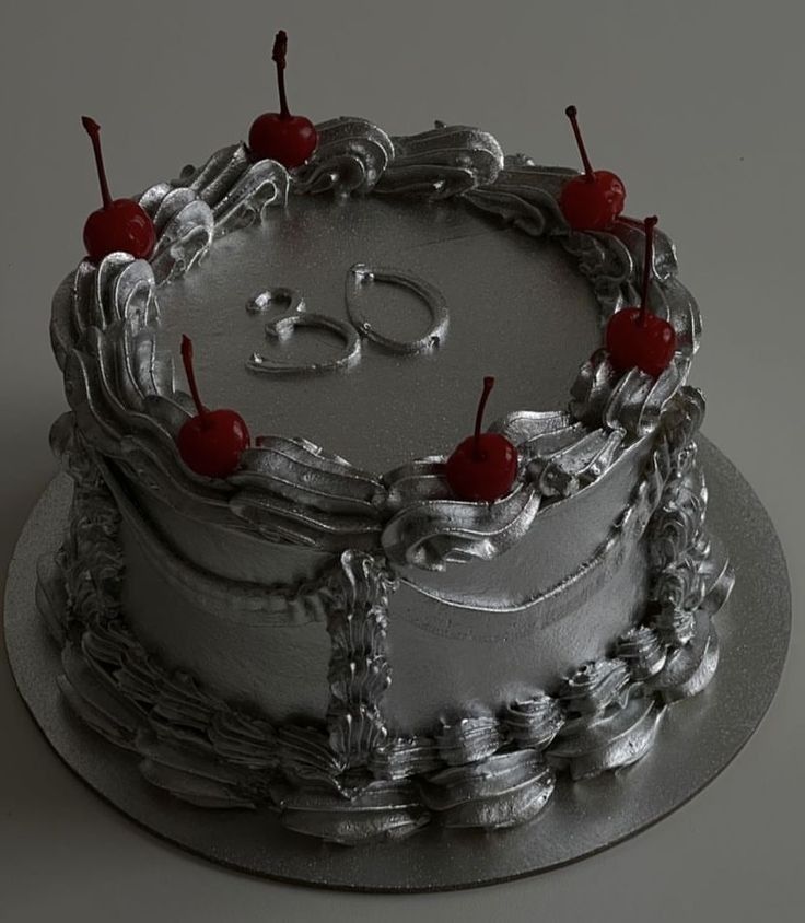 a silver cake with cherries on top