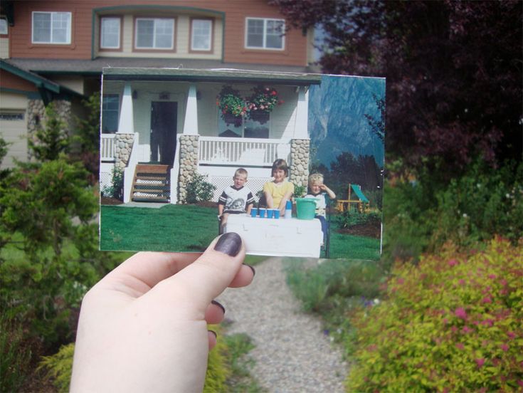 a person holding up a polaroid photo in front of a house with two children