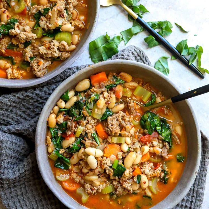 two bowls of soup with meat and vegetables