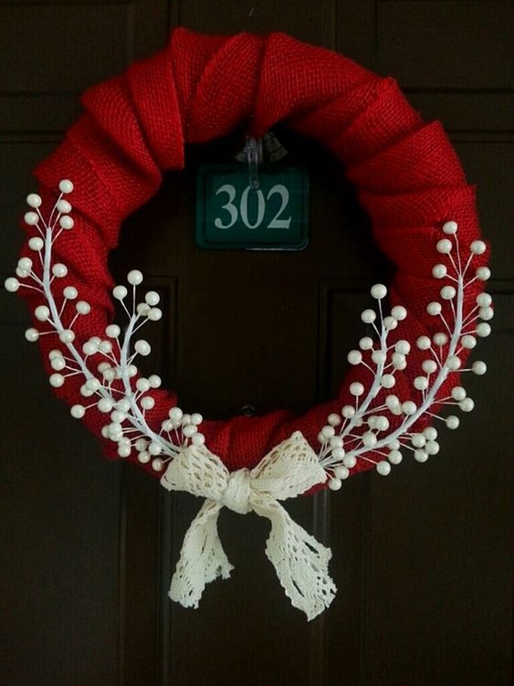 a red wreath with white pom - poms hangs on the front door