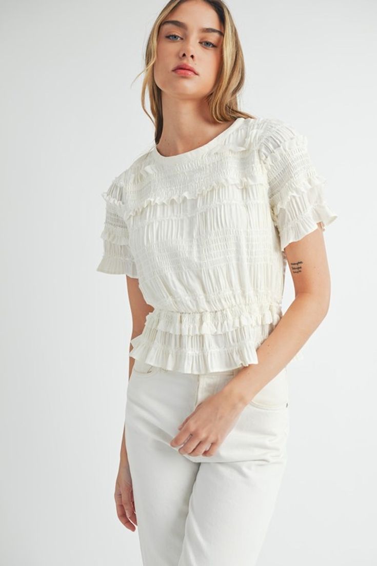 This white peplum top features a stylish mix of ruffled and smocked details, along with short puff sleeves. Elevate your wardrobe with this versatile piece, perfect for both casual and formal occasions. round neckline lined smocked 100% polyester Luxury Elegant Smocked Top, Affordable White Short Sleeve Smocked Top, Luxury Smocked Top With Gathered Sleeves For Spring, Cheap Spring Smocked Top With Smocked Cuffs, Cheap Summer Smocked Top With Smocked Cuffs, Cheap Stretch Smocked Top With Smocked Bodice, Luxury Chic Smocked Top, Chic Smocked Top For Spring, Luxury White Tops With Smocked Bodice