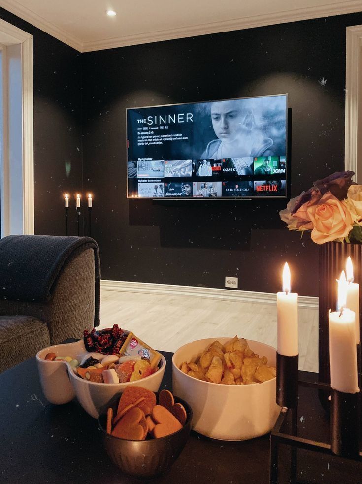 a living room with candles and food in front of a flat screen tv on the wall