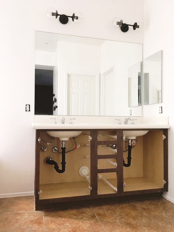 a bathroom with two sinks, mirrors and pipes on the counter top in front of it