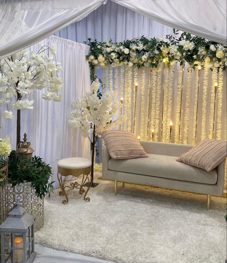 a couch sitting under a white canopy covered in flowers and greenery on top of a rug