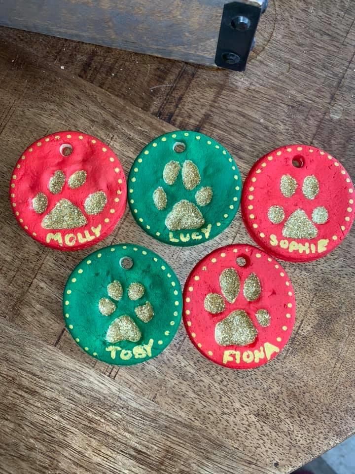 four dogs paw prints on red, green and gold dog id tags with the word'i love you'written on them