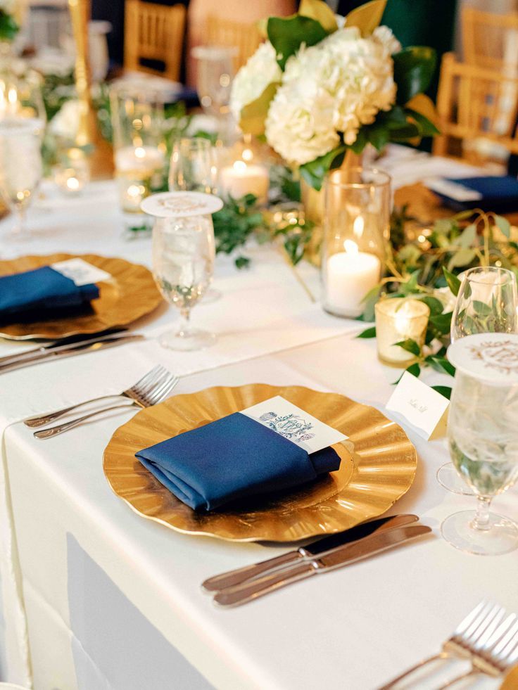 the table is set with gold plates and blue napkins