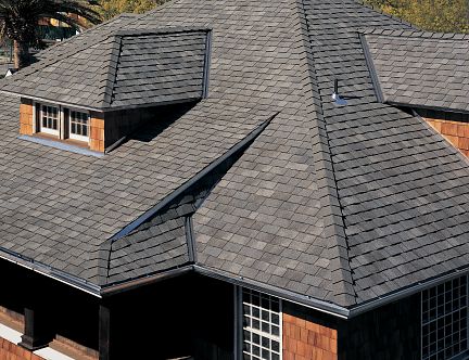 an aerial view of a house with a black roof and brown shingles on it