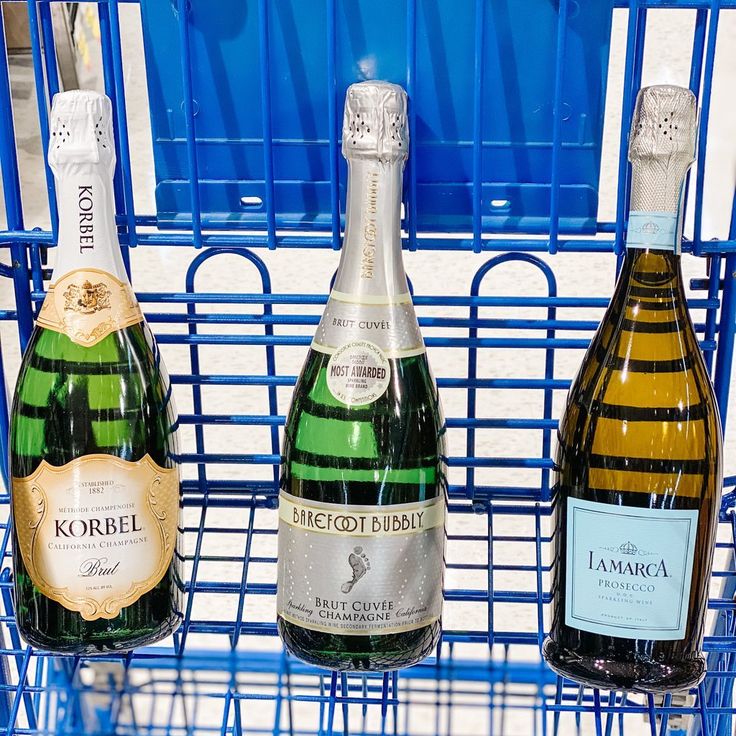 three bottles of wine are sitting in a blue wire basket on the shelf next to each other