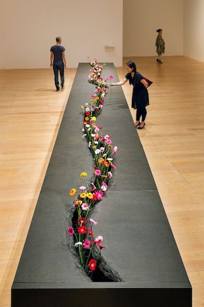 two people walking down a long hallway with flowers on the floor in front of them