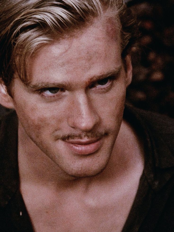 a close up of a man with blonde hair and a moustache on his face