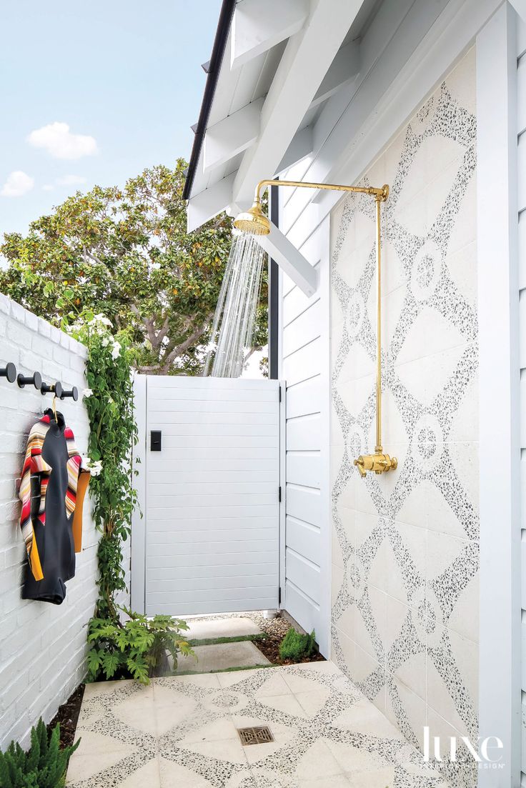 an outdoor shower is shown in this white and gold backyard area with tiled flooring