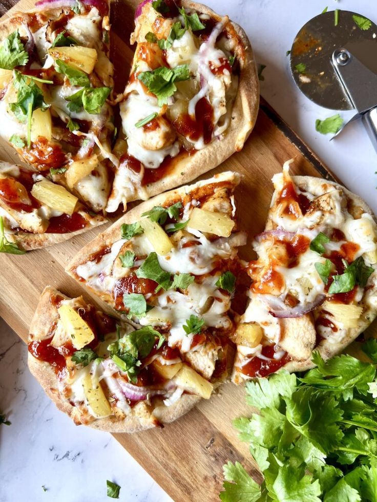 two pizzas with toppings sitting on top of a wooden cutting board next to some parsley