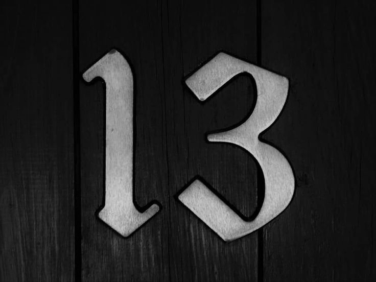 the number thirteen is etched in metal on a wooden door with an arrow pointing to it