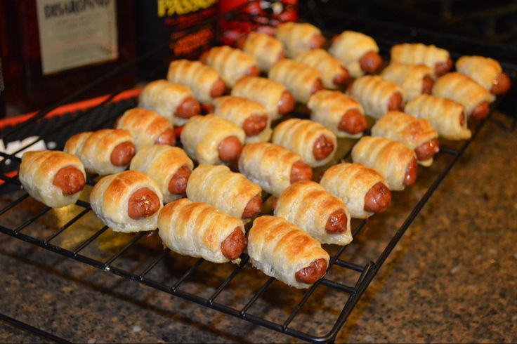 there are many hotdogs on the grill and one is wrapped in croissants