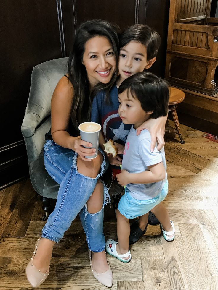 a woman and two children sitting on a chair with a coffee cup in their hands