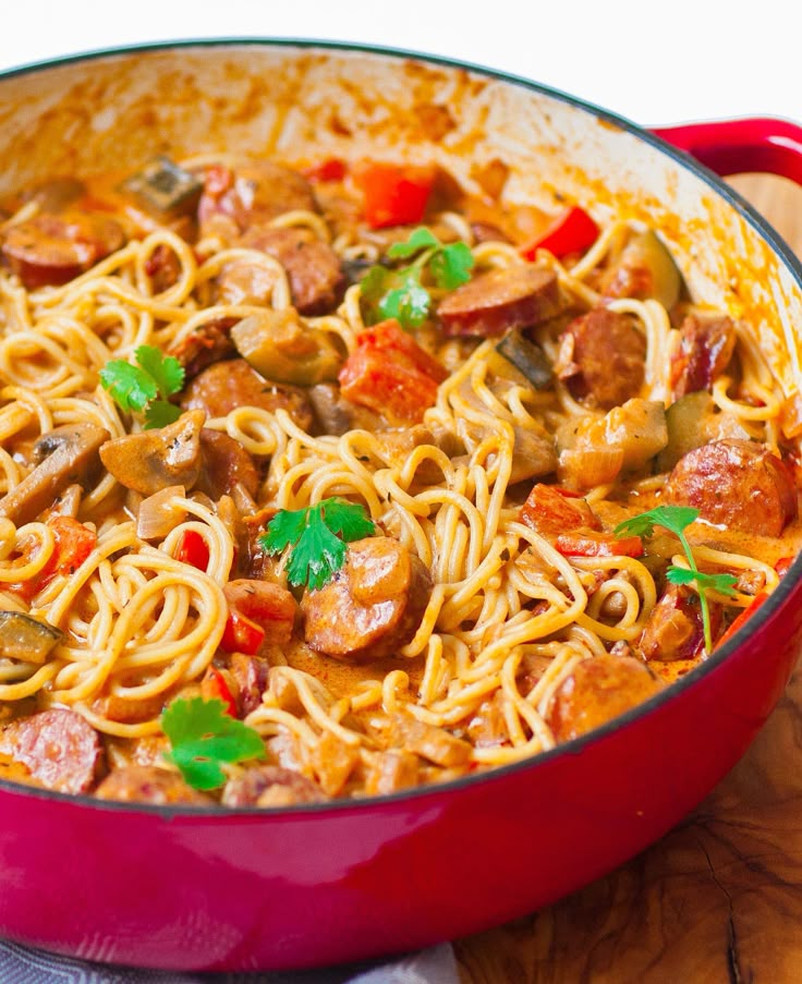 a red pot filled with pasta and sausage