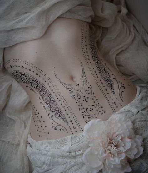 the back of a woman's body with tattoos and flowers on her chest,