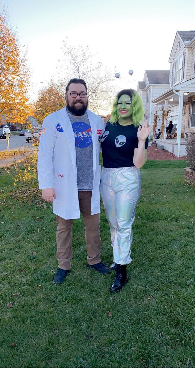 a man and woman dressed up in costume standing on the grass with one hand out