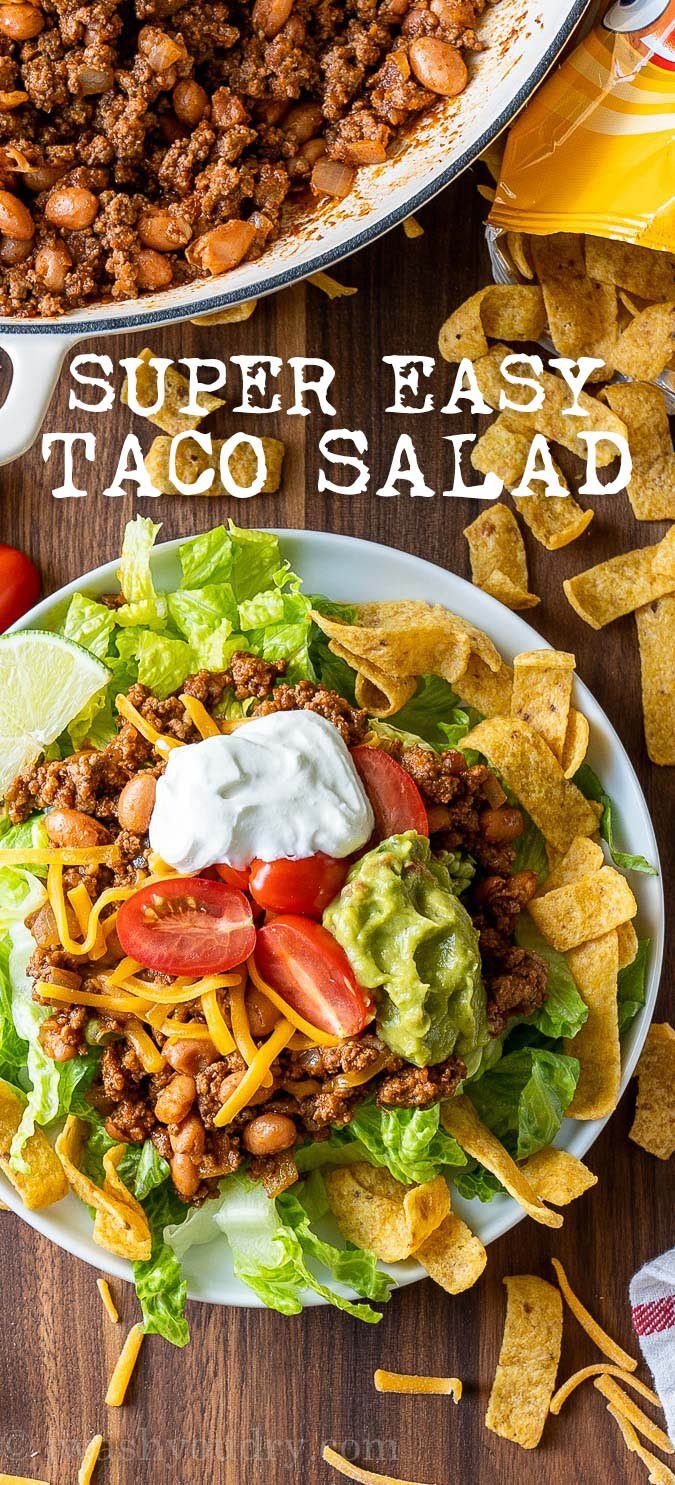 a taco salad with lettuce, tomatoes, cheese and beans on it