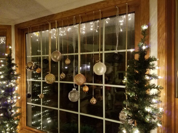 a window with christmas decorations hanging from it's sides and lights on the windowsill