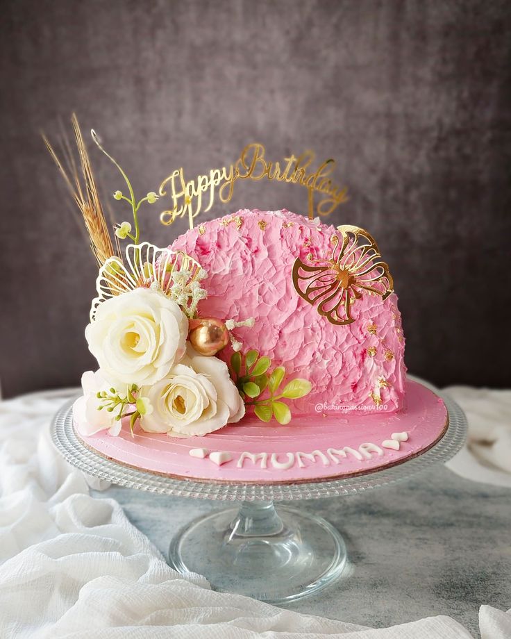 a pink birthday cake decorated with flowers and a butterfly topper that says happy birthday