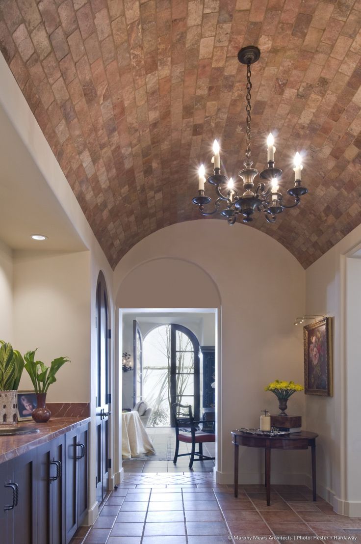 a long hallway with a chandelier hanging from it's ceiling and tiled floors