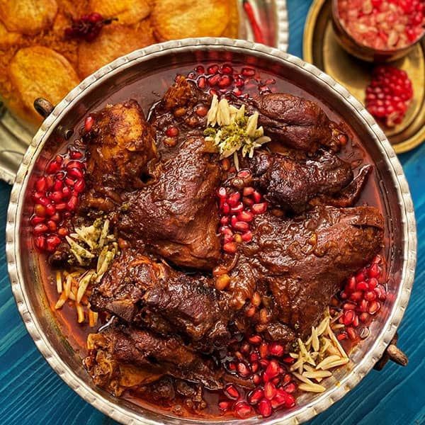 a bowl filled with meat and pomegranates on top of a table