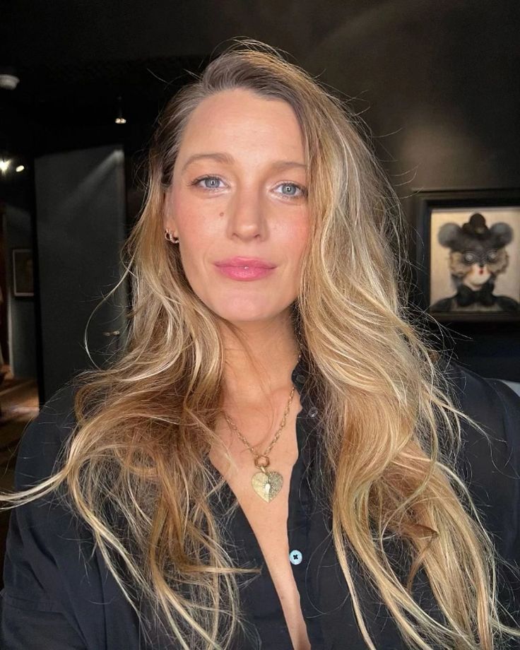 a woman with blonde hair and blue eyes posing for a photo in a black shirt