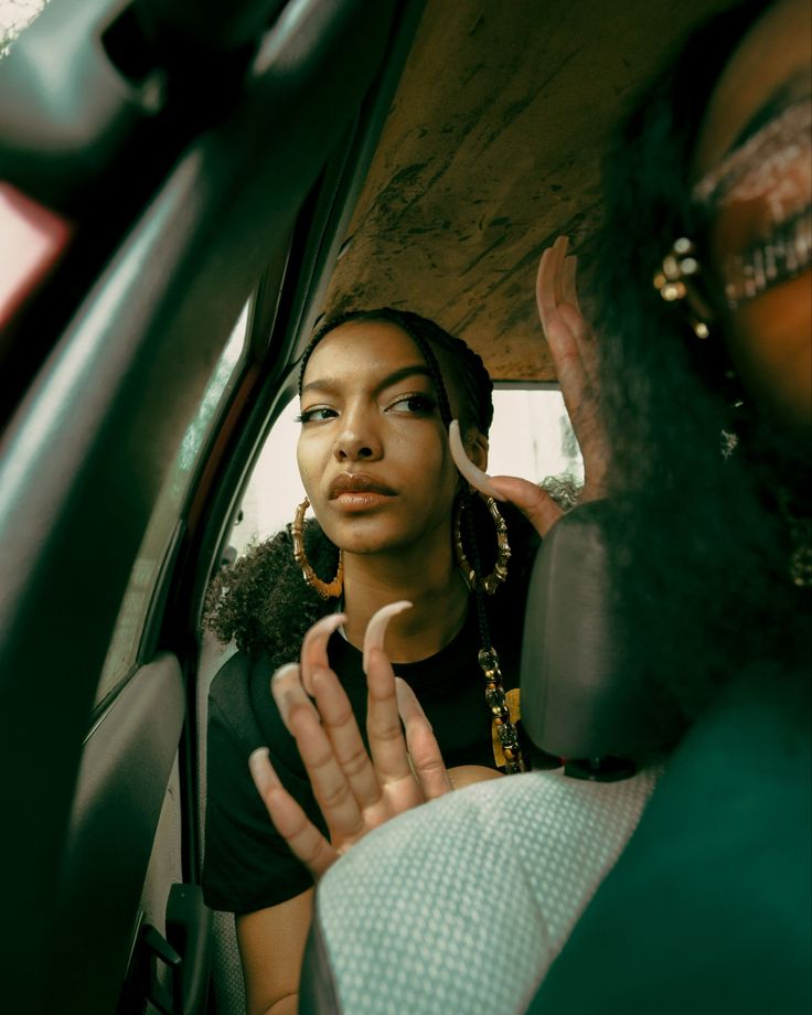 a woman sitting in the back seat of a car with her hand up to her face