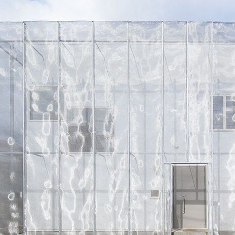 a cat sitting on the ground in front of a building with plastic covering it's windows