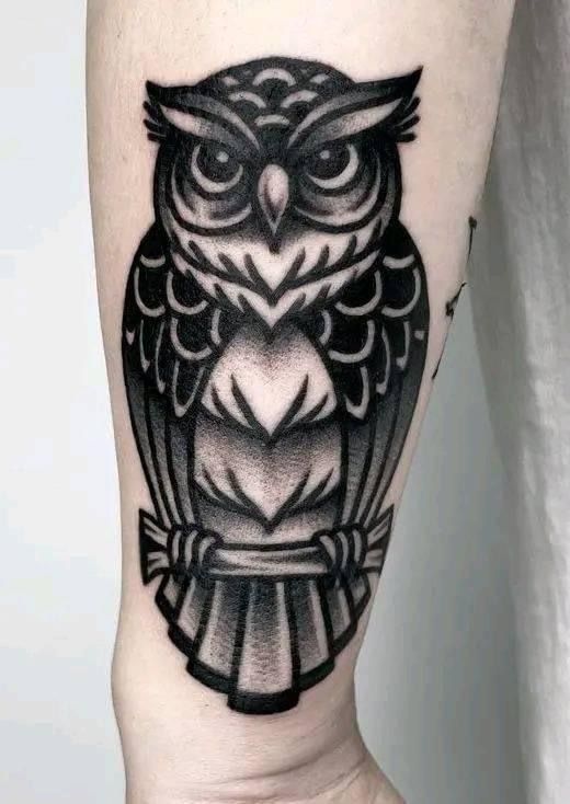 an owl tattoo is shown on the leg and it's black and white color