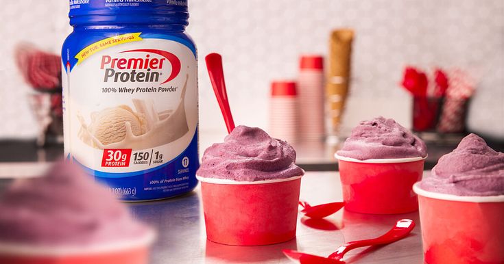 three ice cream cups sitting on top of a counter next to a jar of protein powder