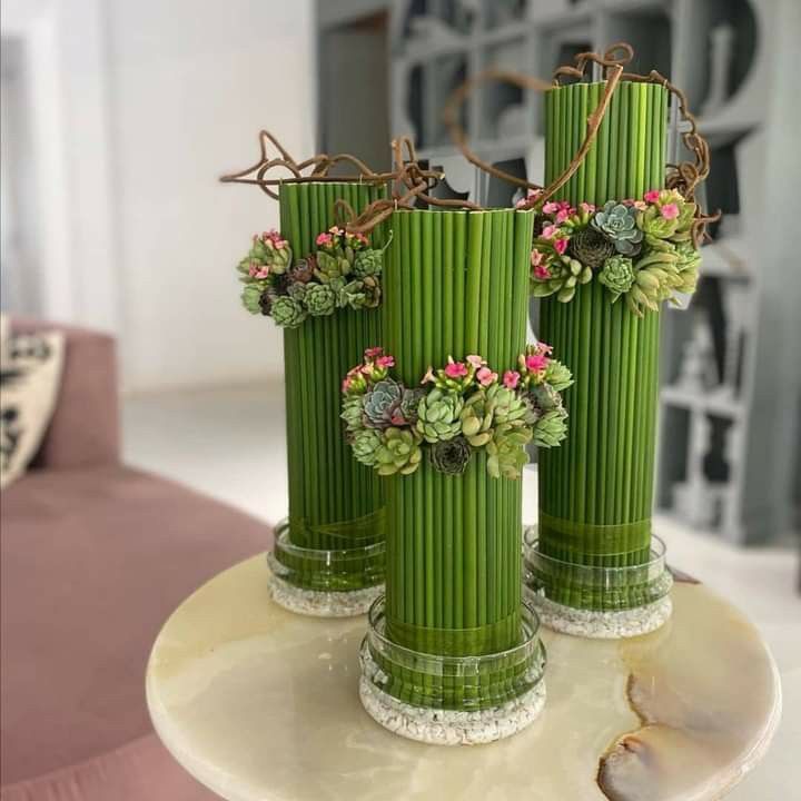 three green vases with plants in them on a table