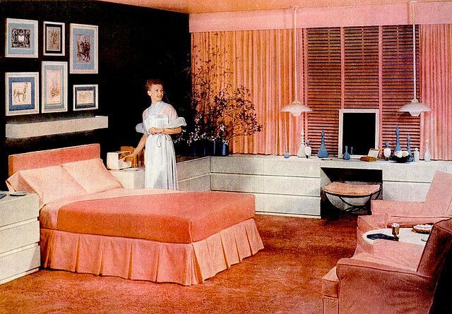 a woman standing in the middle of a bedroom next to a bed and dressers