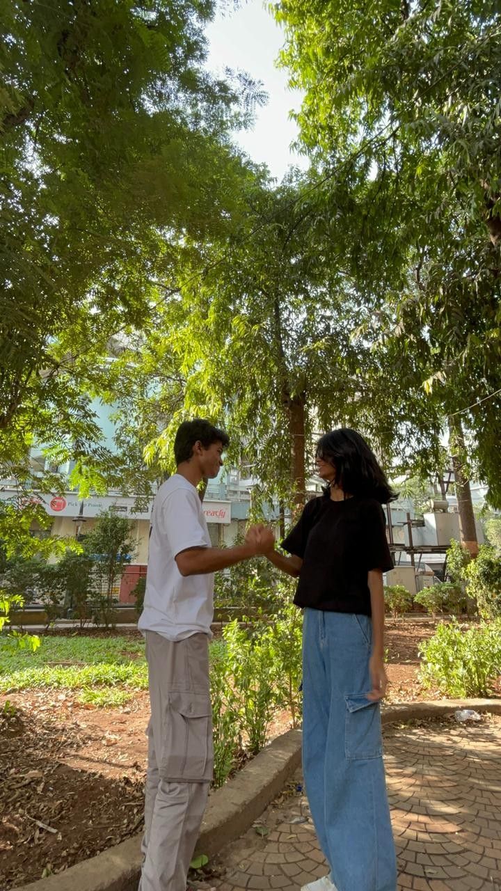 two people standing near each other in the park, one holding onto another person's leg