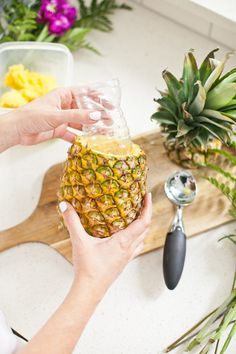 a person holding a pineapple in front of a cutting board with fruit on it