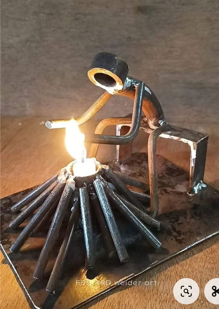 a candle holder made out of sticks and a man sitting on top of it with a lighter in his hand