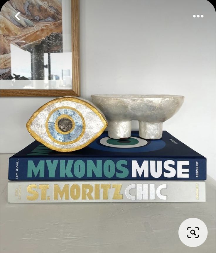 two books are stacked on top of each other in front of a mirror and bowl