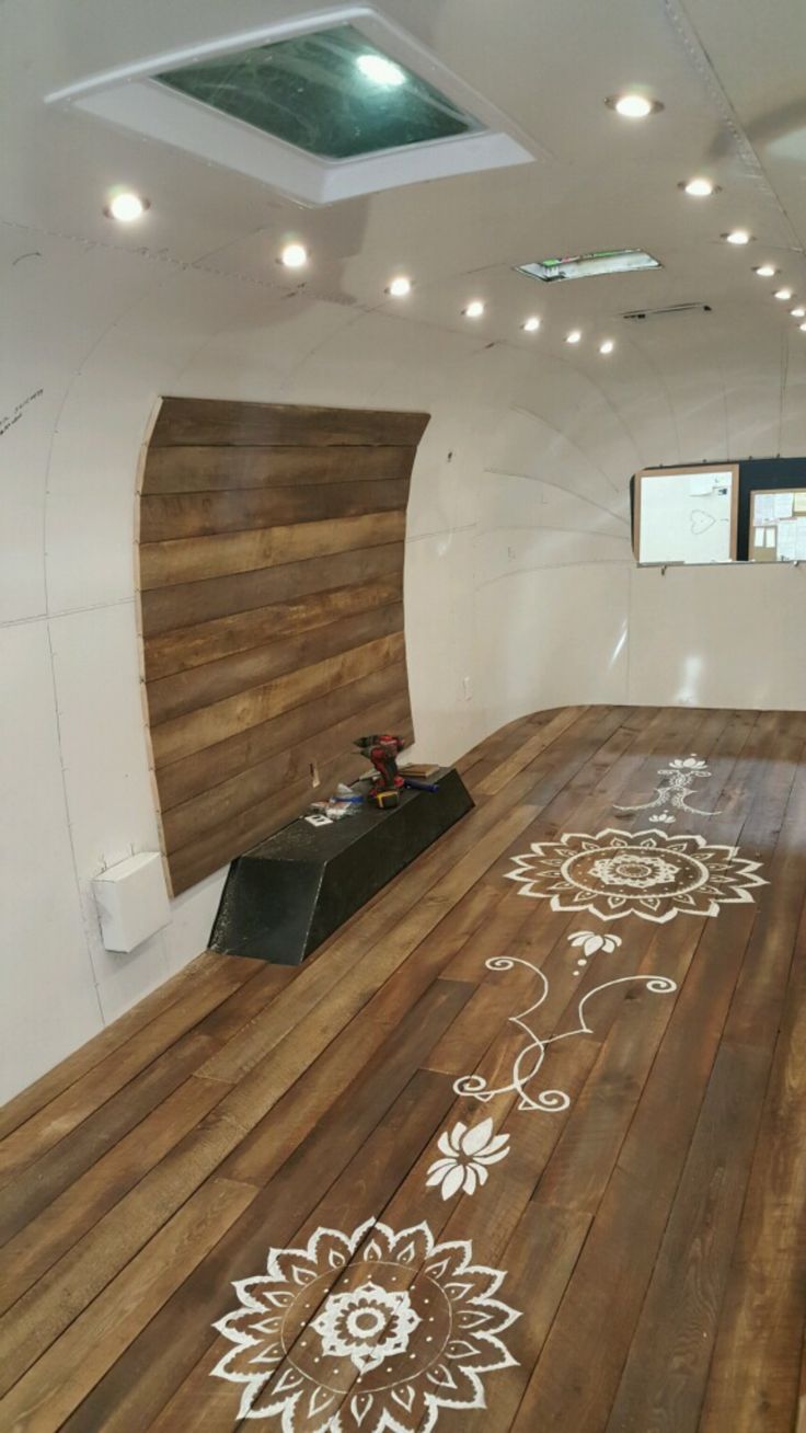 an empty room with wooden floors and white painted designs on the floor, along with a projector screen